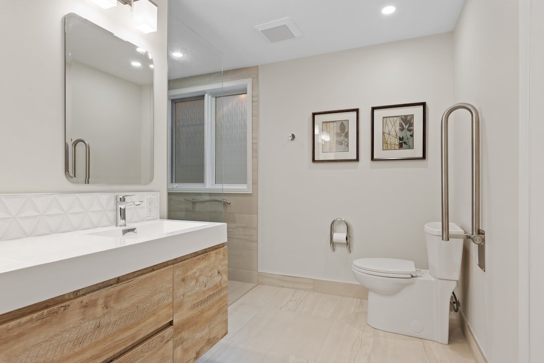 An older adult using a grab bar in a bathroom to prevent falls, with non-slip mats and clear space around the shower area.