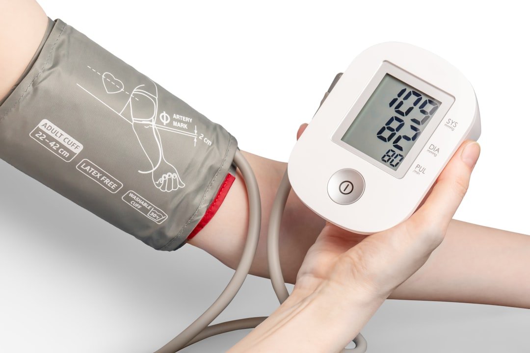 A person measuring their blood pressure at home using a digital monitor.