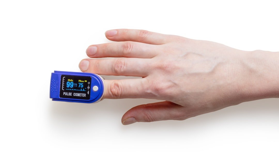 A close-up of a pulse oximeter on a person's finger, displaying readings of blood oxygen saturation and pulse rate, in a home health setting.
